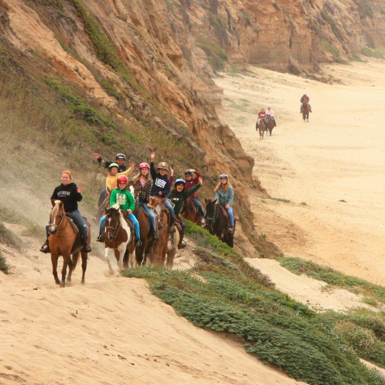 Riders waiving at the camera on a Horse back ride